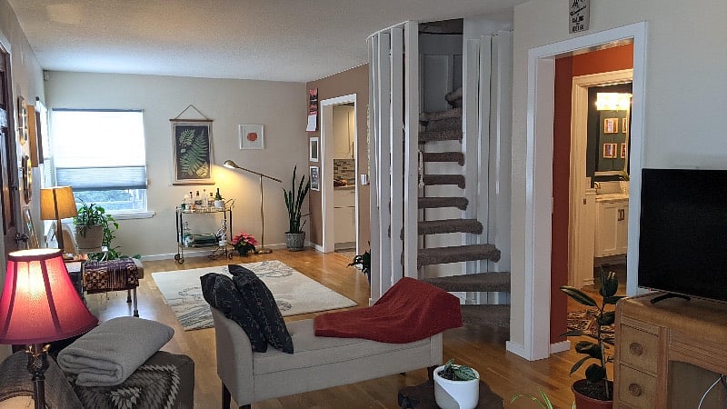 View up the stairs, of the left side of the living room, and into the small hallway that contains the office/guest room, and the main bathroom.