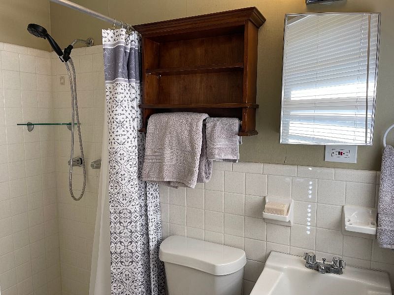 The en-suite master bathroom has a tiled shower, commode and vanity, and features brand-new linens.