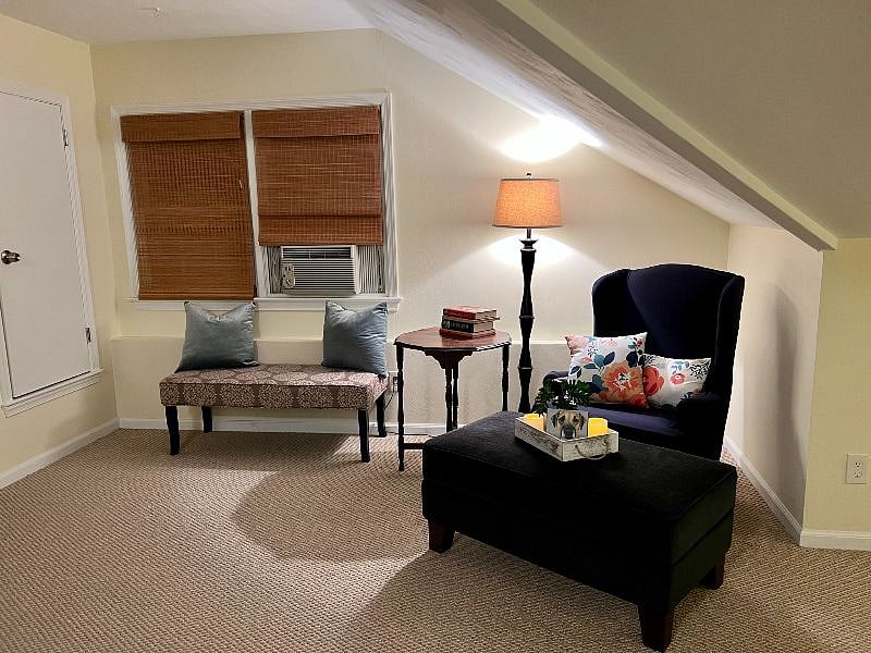 Living area with comfy chair and storage ottoman.