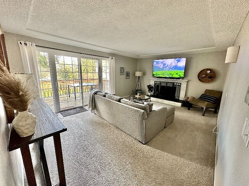 Living room with 65" smart TV with entry to deck overlooking large fenced in backyard.