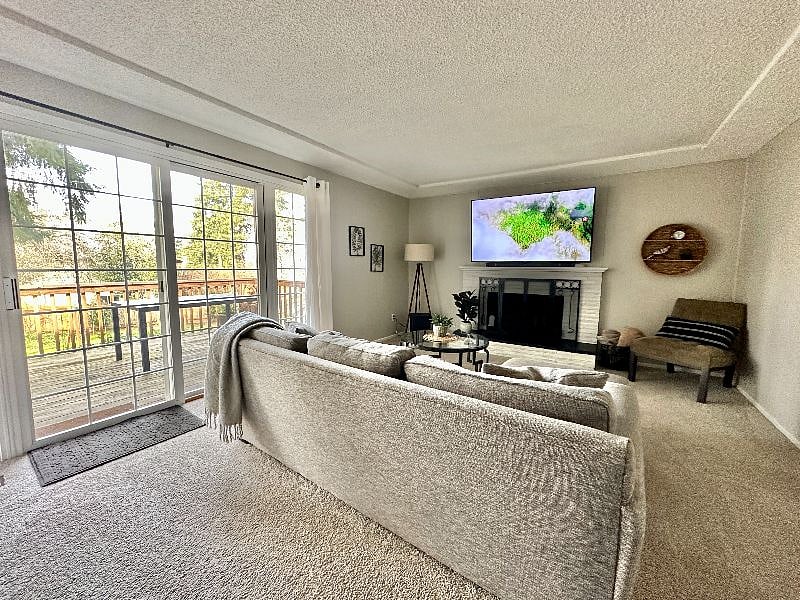 Living room with 65" smart TV with entry to deck overlooking large fenced in backyard.