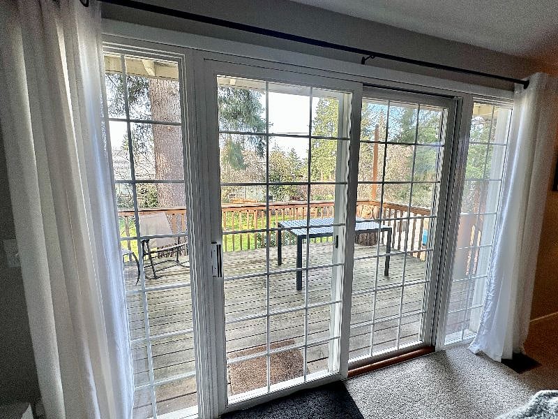 Living room with 65" smart TV with entry to deck overlooking large fenced in backyard.