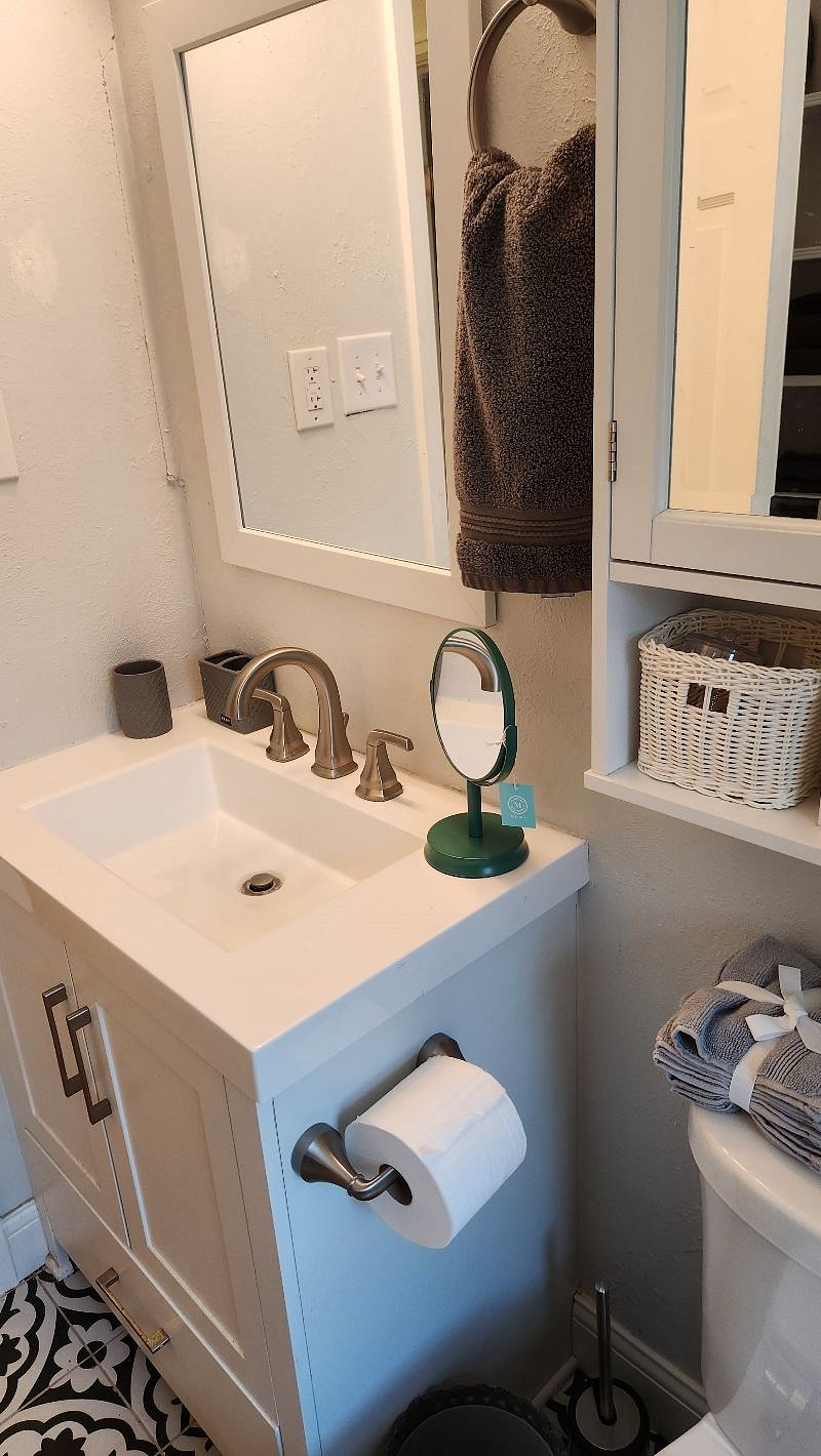 bathroom sink and wall-mounted 'medicine' cabinet with storage baskets