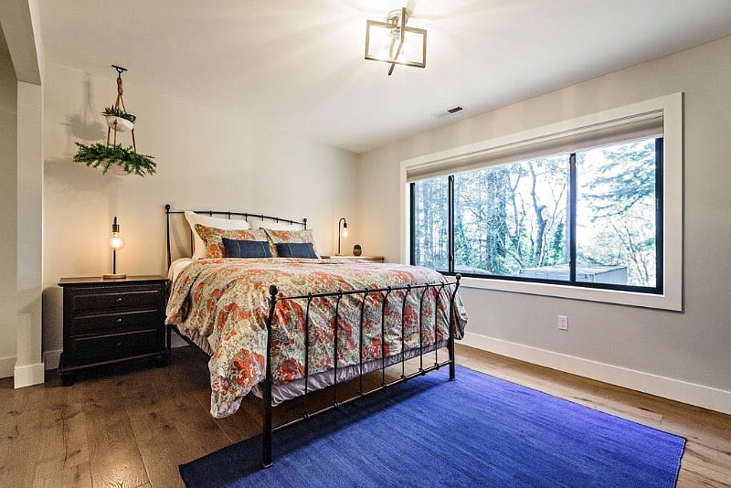 Queen size bed and spacious bedroom with oversized window overlooking large backyard