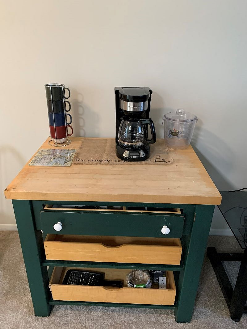 Dining service table with coffee maker, mugs and kitchenware.