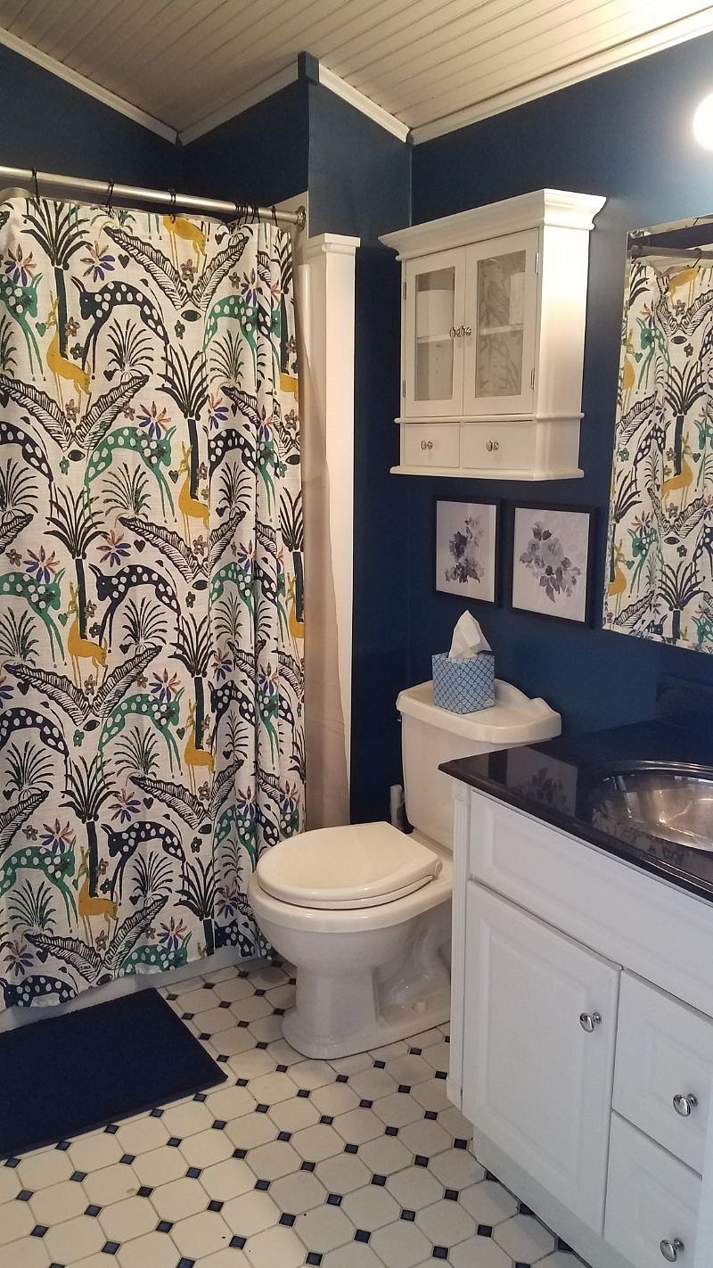 Tiled bathroom with large mirror and stainless sink.