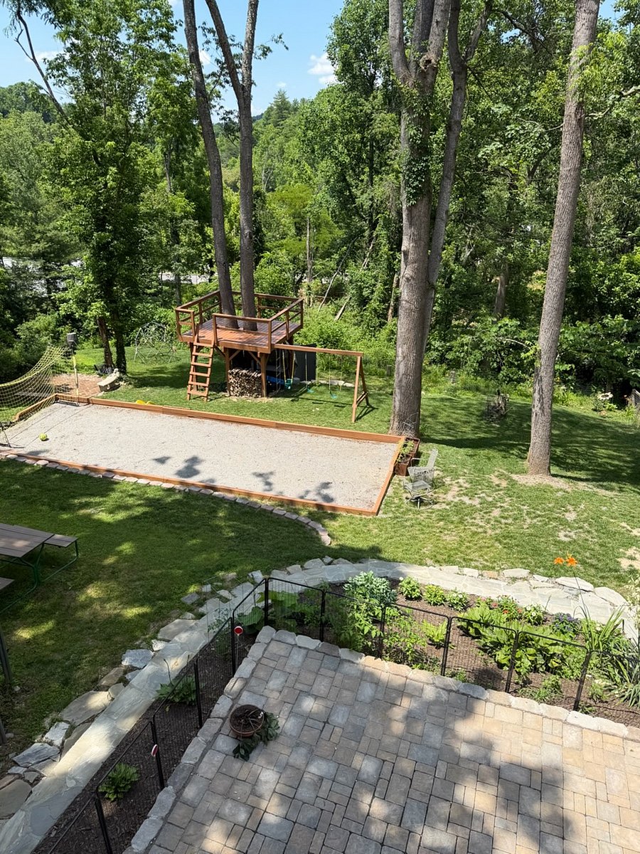The backyard boasts a variety of activities for all ages including a multi-purpose court with gear for bocce, badminton, and soccer practice, a fire pit, tree fort with swings, slide, climbing wall, and geodesic climbing structure.