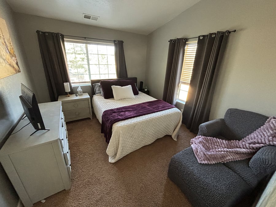 Bedroom 2 has queen bed, dressers, closet, smart TV and cozy chaise lounger.