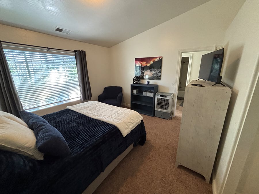 Bedroom 3 has queen bed, dressers, closet, smart TV and cozy chair and bookcase.