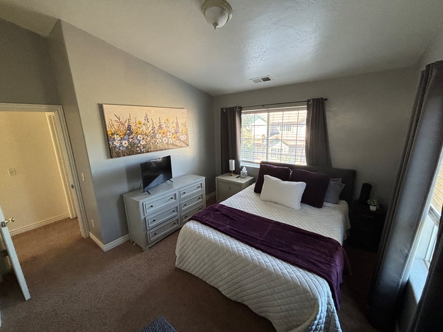 Bedroom 2 has queen bed, dressers, closet, smart TV and cozy chaise lounger.