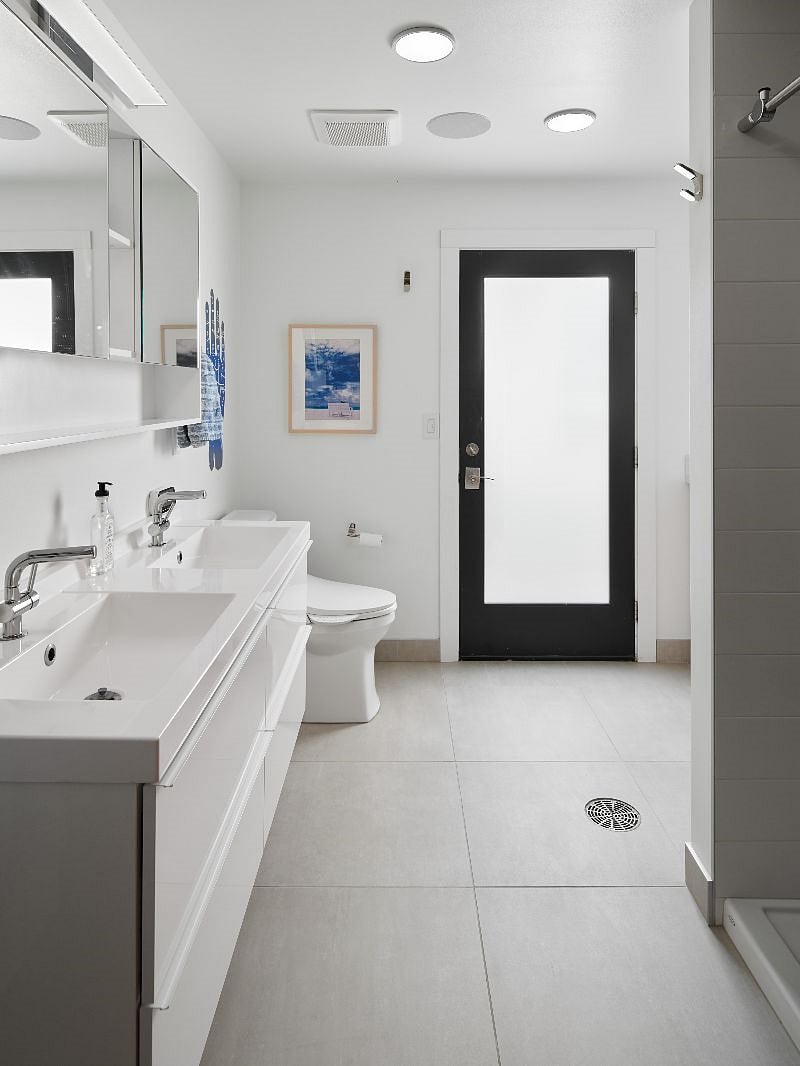 A large bathroom (shared) includes double sinks, a bidet toilet and a door to the oversize outside deck and saltwater pool