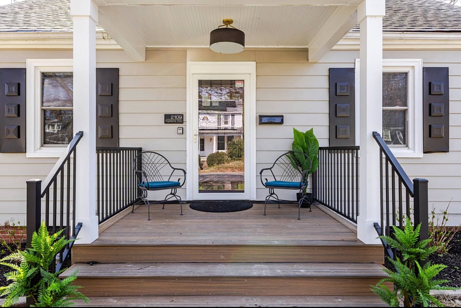 Charming entry porch with iron chairs and ferns.