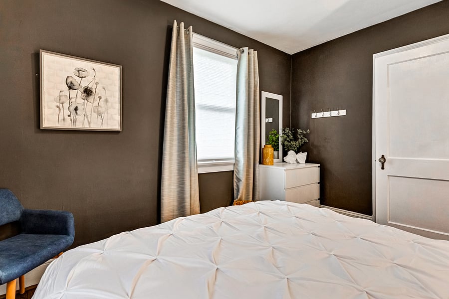 Designer bedroom with beautiful art, a comfortable bed and plenty of natural light.