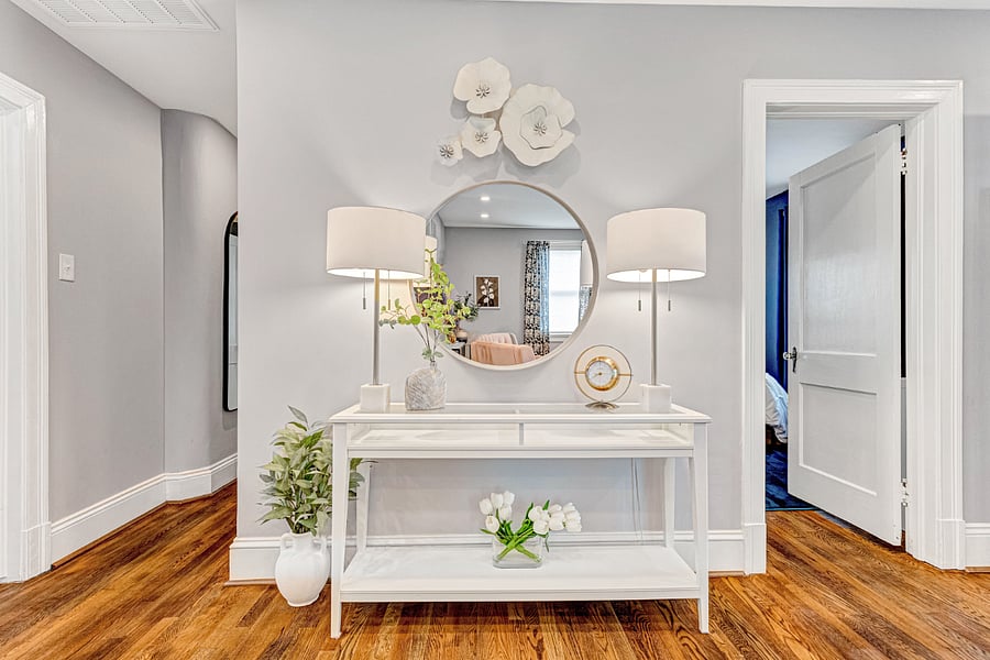 Designer entryway with a gold clock, mirror and elegant lamps.