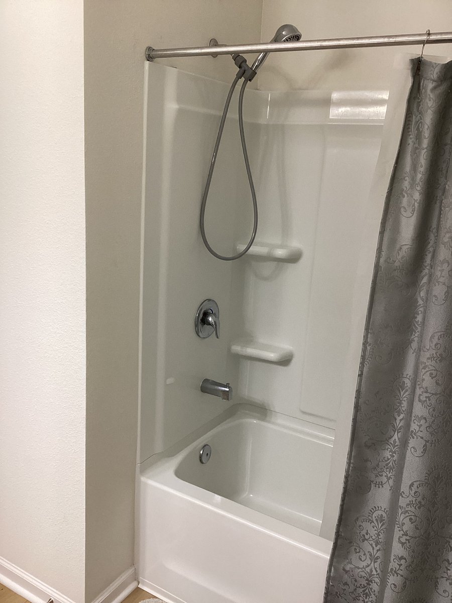 BATHROOM - View of shower unit, bathtub and shower curtains.