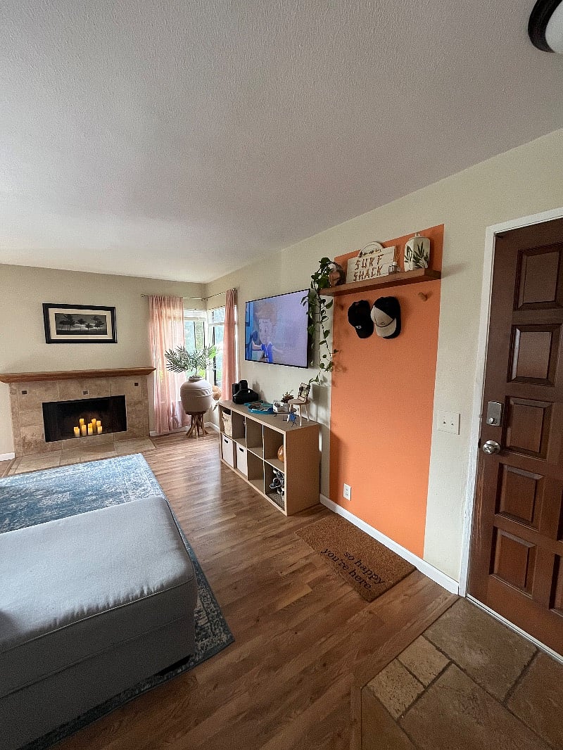 View of the brown front door, a cute hook nook, living room TV, and working fireplace