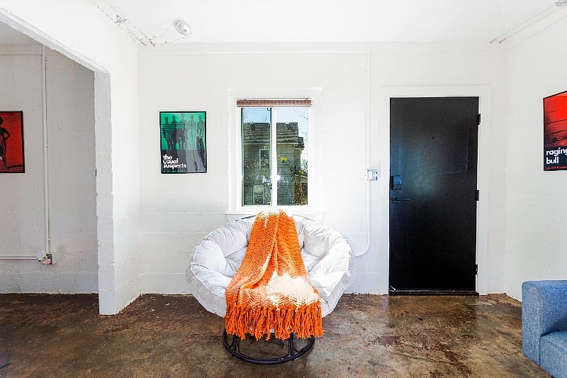 Comfortable papasan chair in the living room with a cozy rust-colored throw. Note custom movie poster on the wall.