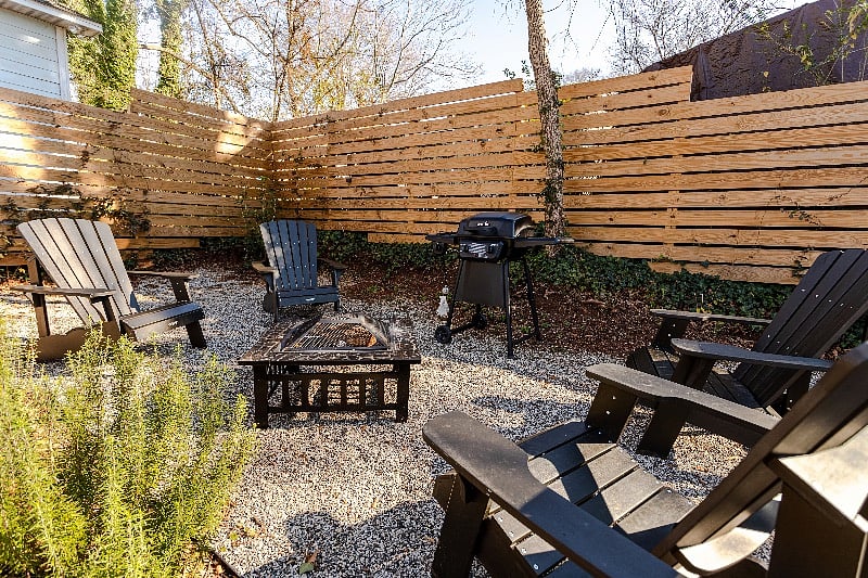 Firepit, grill, and chairs in backyard. 