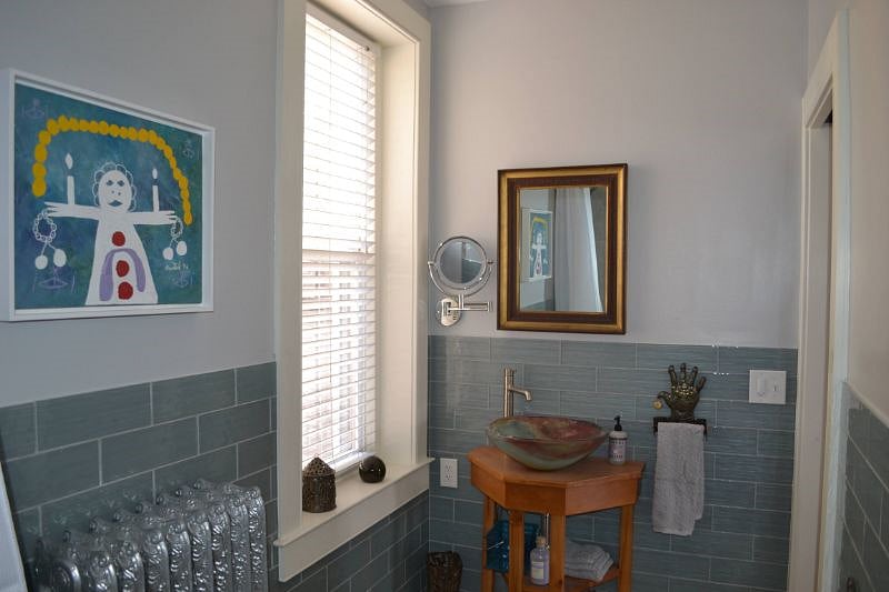Bathroom has a large window and Gravity Glass vessel sink. 
