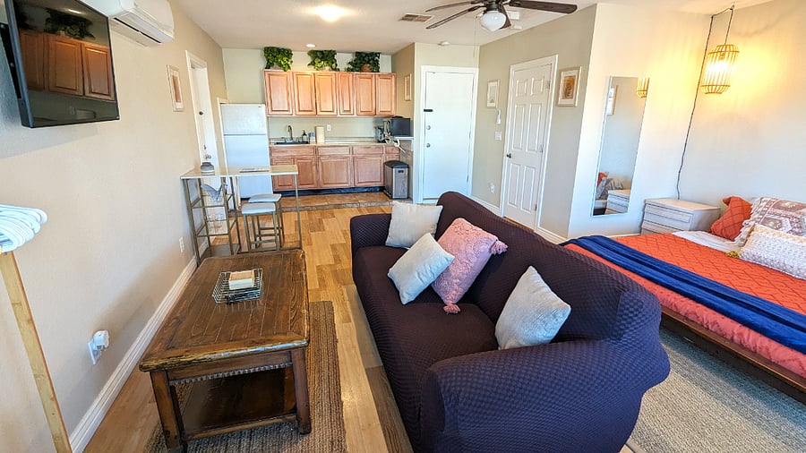 Overview of bed, kitchenette, living area and doors to the bathroom and laundry room.