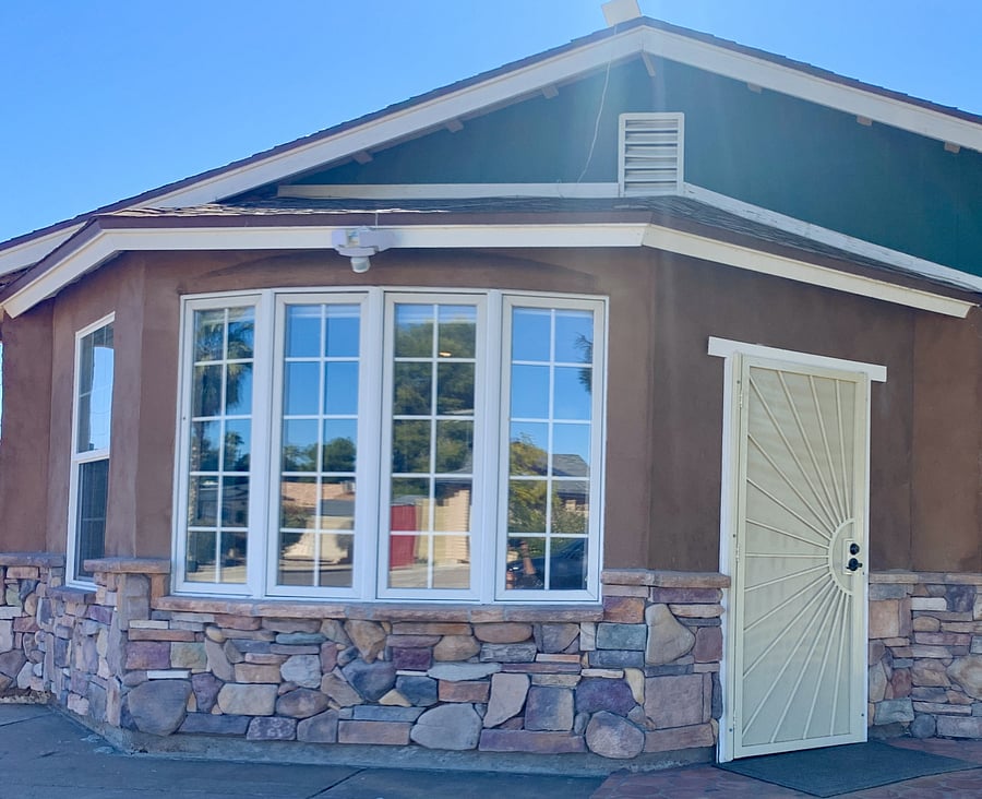 Front entryway with large bay windows and sun design security door.