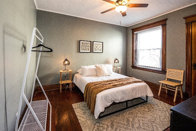 Bedroom #1 with a memory foam queen mattress, large dresser, and clothing rack.
