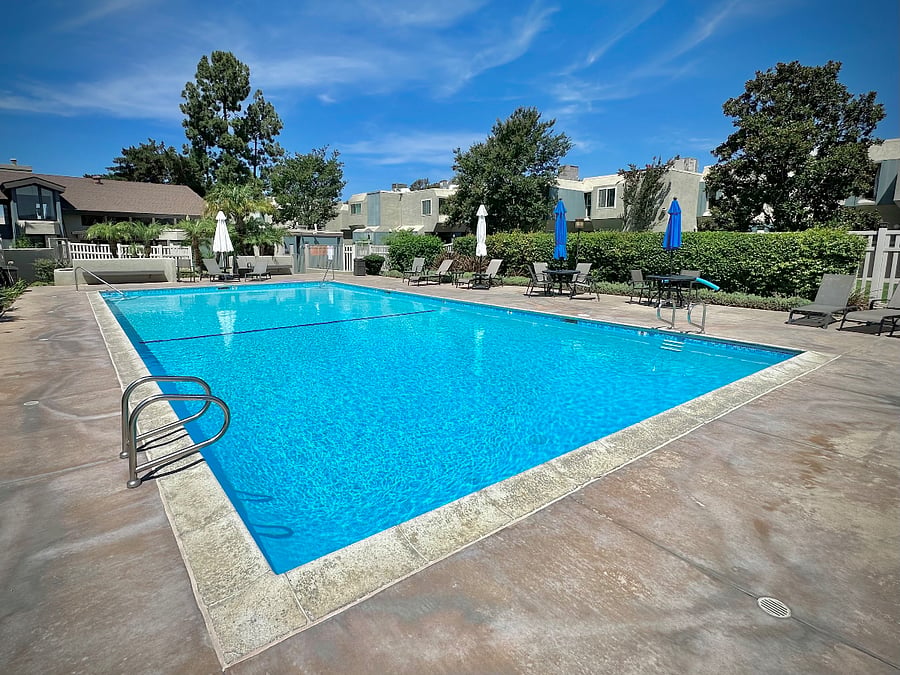 Community pool with lounge chairs, tables and shade umbrellas.