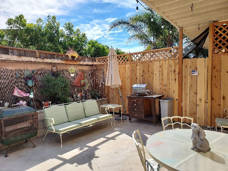 fenced private backyard with table w/4 chairs, couch, chair, Propane BBQ and gate that goes out to sidewalk to beach and wood burning firepit.