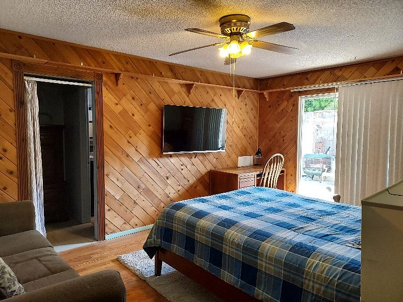master bedroom with queen bed, TV and walk in closet, desk and slider that goes out to backyard
