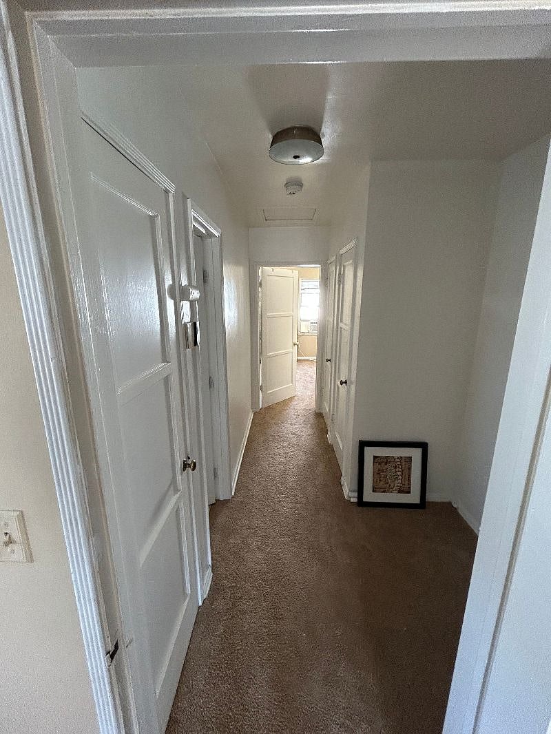 Hallway connecting the two bedrooms, with the bathroom entrance to the left and the entrance back into the living room on the right.