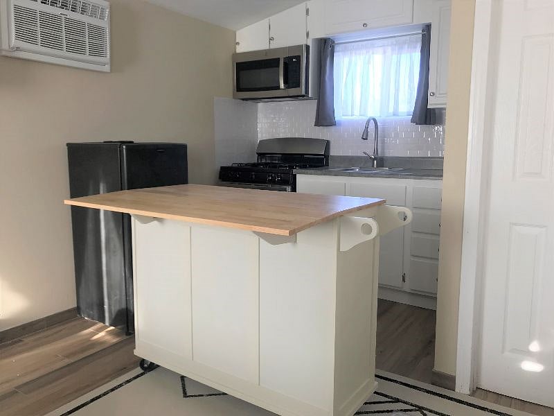 Kitchen Island cart with a drop leaf for additional counter space. This can be wheeled out, as needed.