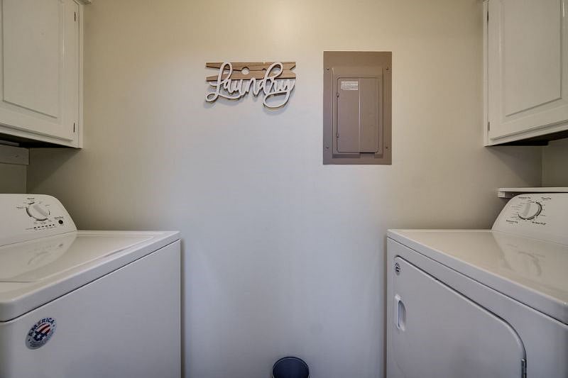 Laundry room on the main level with a full-size washer and dryer, plus cabinets above to store supplies.