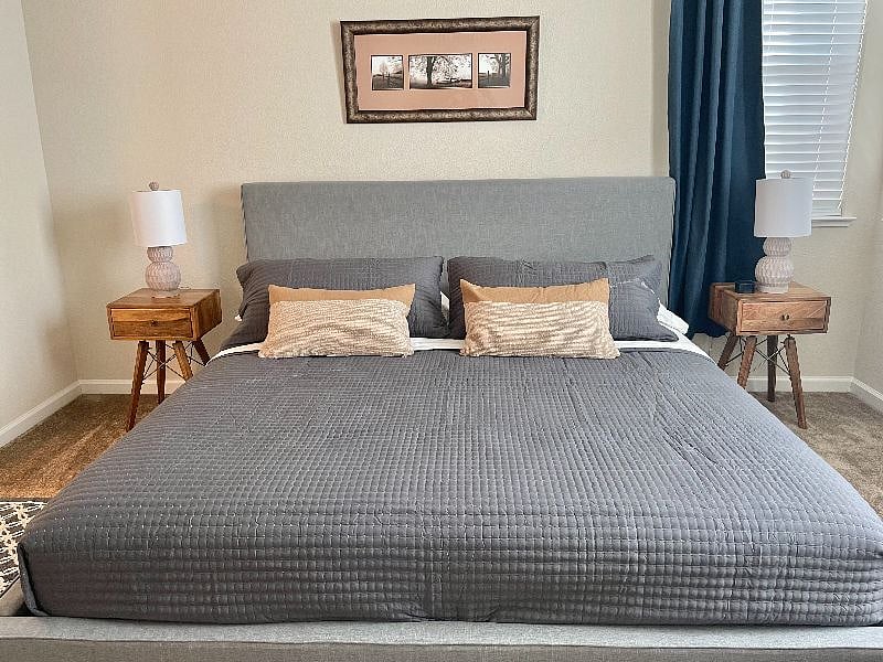 Master bedroom with King size bed, ceiling fan, black out curtains, and a white noise machine.