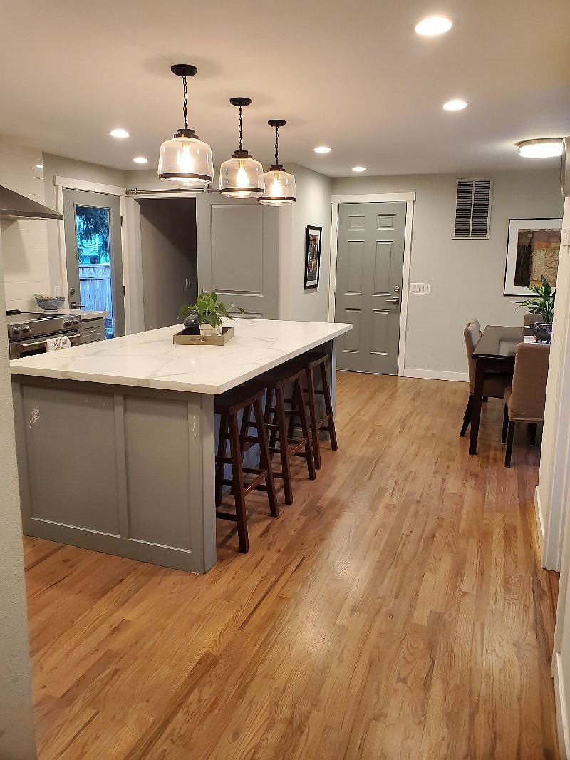 Door to patio and backyard and next to it is laundry room with newer appliances, ironing board and iron