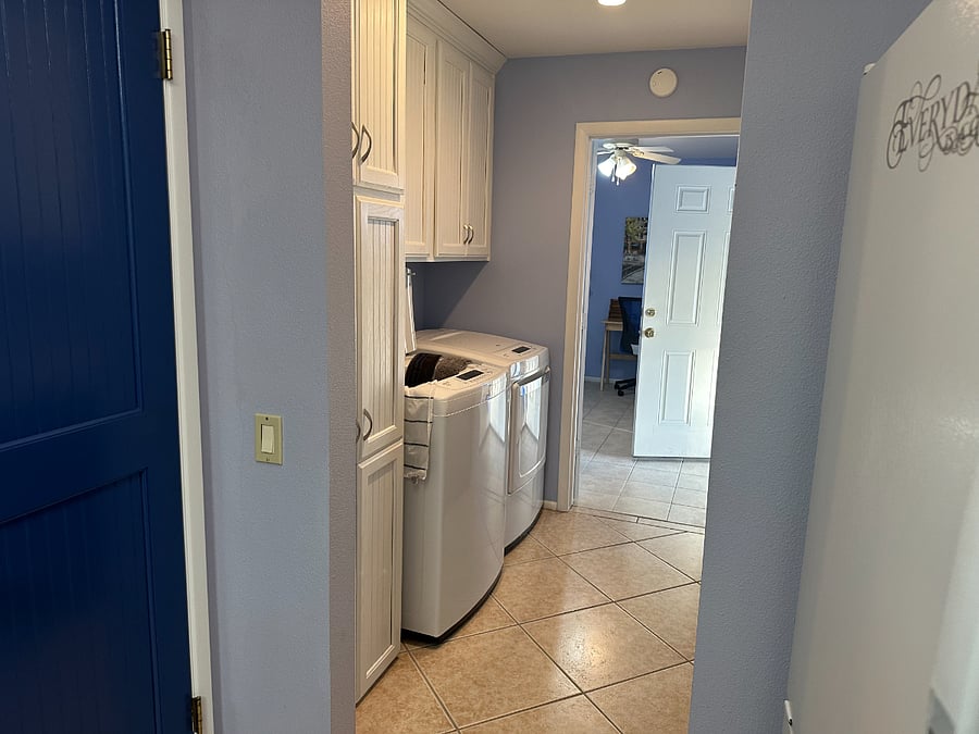 Convenient laundry area with laundry soap and a long folding counter and clothes hanging area.