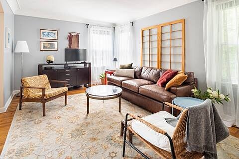 Living room with smart TV, windows for light, leather couch for snoozing