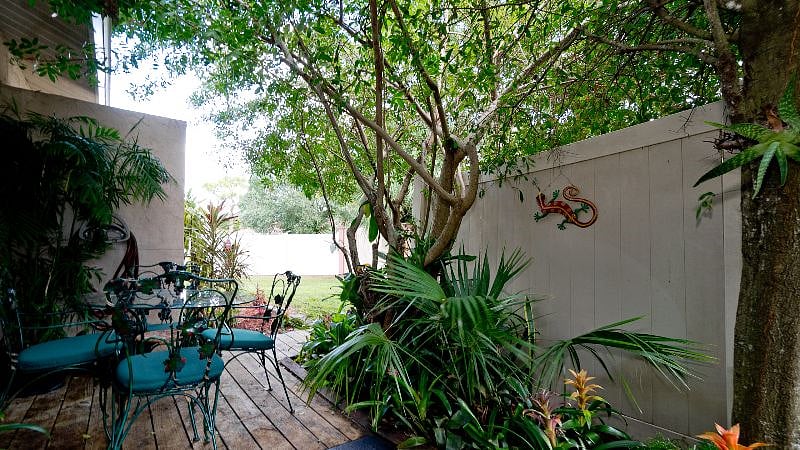 Patio with sliding glass doors to the kitchen, cafe table and chairs, mature foliage, sometimes  orchids, bromeliads, and a barbecue grill is really not included ( condo rules,) but Almost definitely will be there