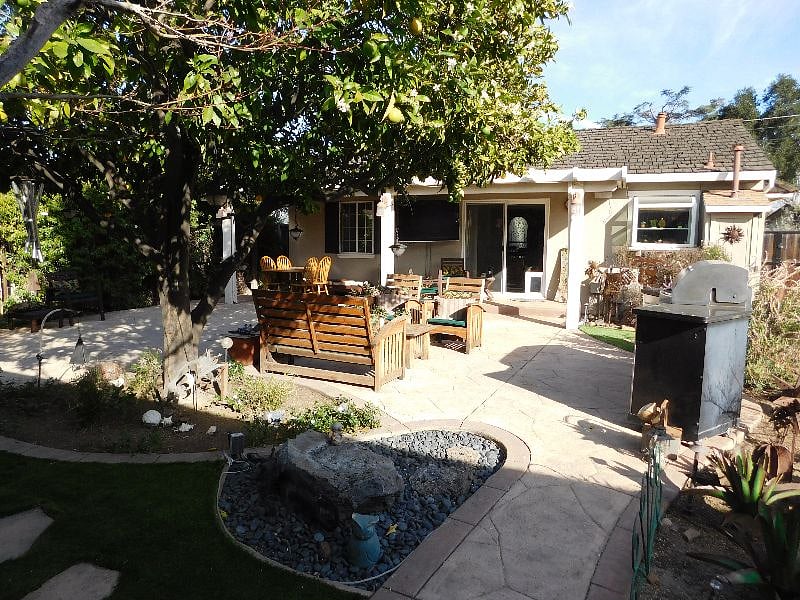 Private backyard with water feature, large BBQ, and teak patio furniture.