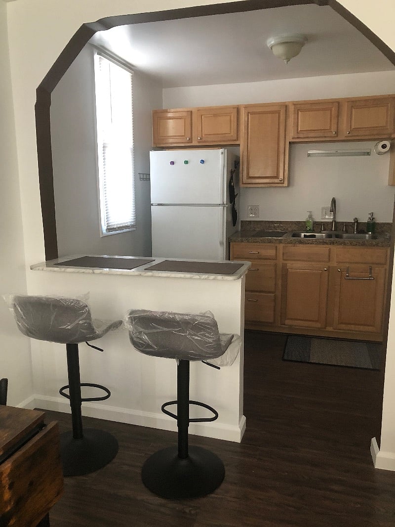 Kitchen counter with swivel adjustable seats. Stocked with microwave, toaster, blender, drip coffee maker, crockpot, coooking pots, pans, glassware, and utensils.