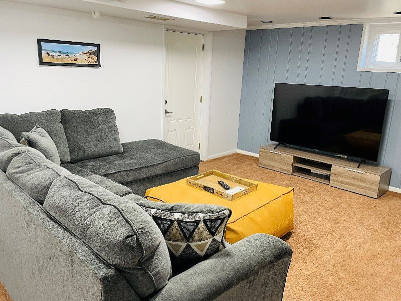 Gather in this comfortable family room basement featuring a queen sofa sleeper with a memory foam mattress, a brand new 70 inch smart TV, and lots of board games