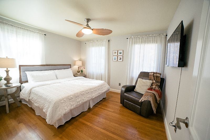 Sleep like a royalty in the main level master bedroom featuring a king sized bed with a brand new Nectar memory foam mattress and pillows, a comfy reclining chair, ceiling fan and a flat screen TV