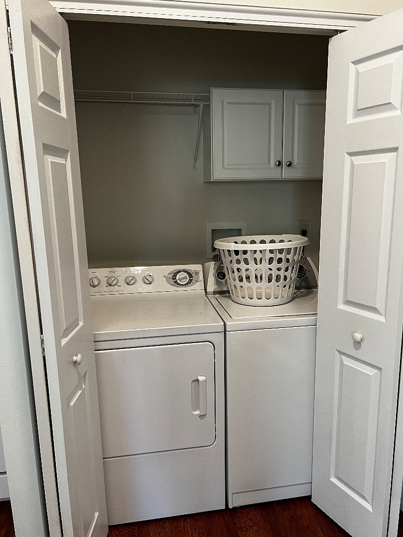 There is a full size washer and dryer with storage cabinets above.