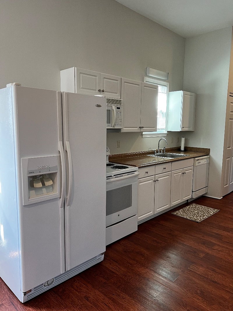 Large kitchen area with a full size refrigerator, microwave, stove, dishwasher, toaster and coffee pot.