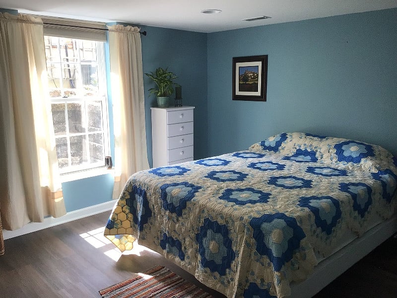 A lovely bedroom newly painted with faux hardwood flooring, a southeast looking window, and a new Queen size bed.