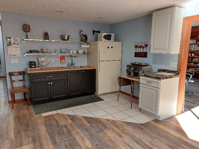 Kitchenette with small appliances, sink, fridge and freezer, stocked dishes and cooking utensils.