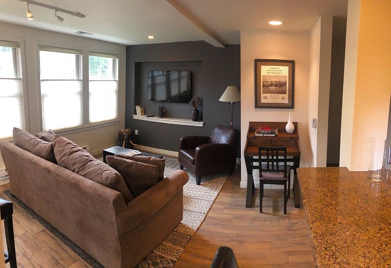 Living room with TV, compact work station, and super comfy sofa. Wall of east facing windows for lots of light.