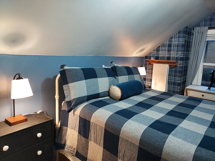 Queen-sized bed in main bedroom, with desk, small dressser, and closet.