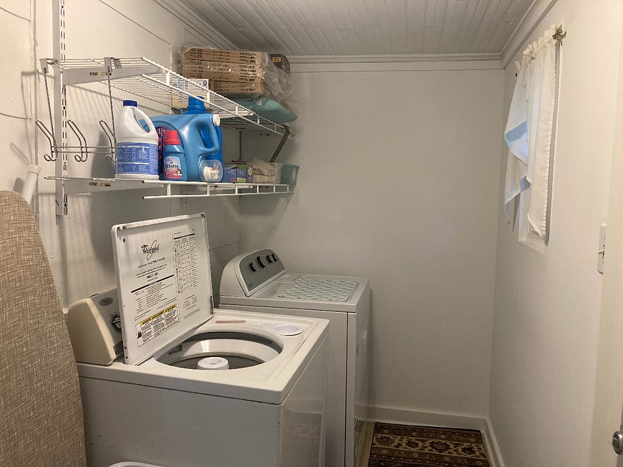 Laundry room with ironing board, iron, broom, vacuum cleaner etc... There is a small window that gets afternoon/evening sun and a backdoor with a storm door that leads to the backyard.