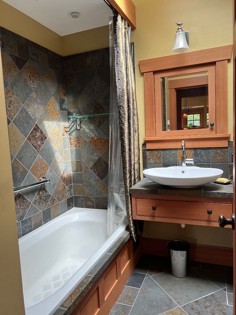Beautifully tiled bathroom with bathtup/shower combo along with skylight and window.