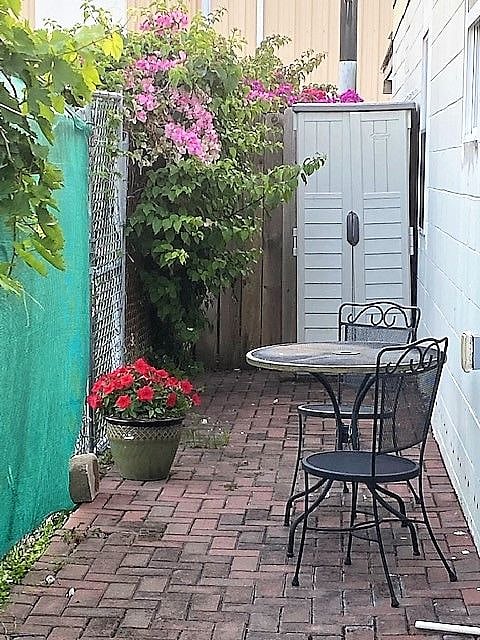 Private bistro table on terrace with side gate to enclosed 1/2 acre lot with fruit trees and bougainvillea